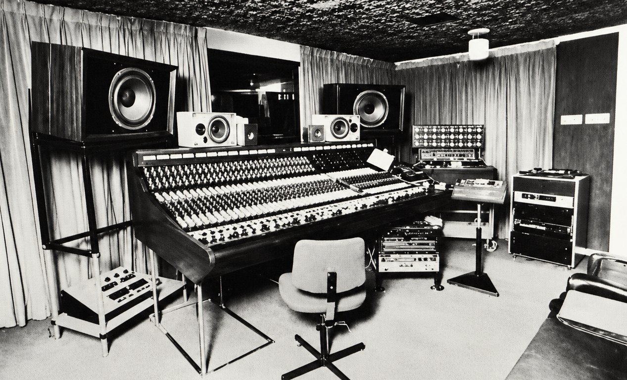 Black and white photograph of a recording studio control room with a large mixing console and studio monitors